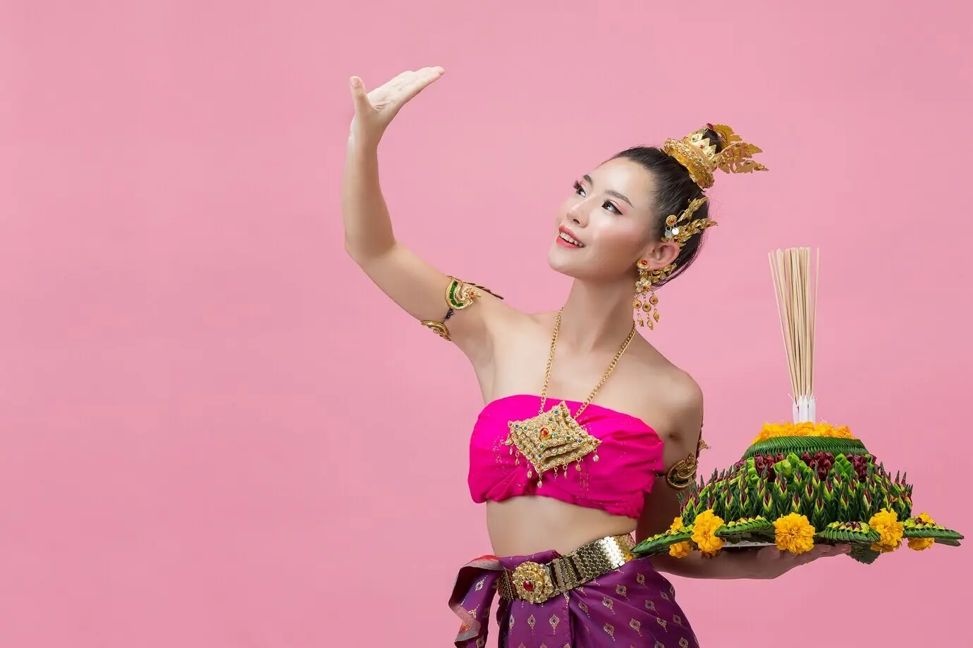 Loy-Krathong-Festival. Eine Frau in traditioneller thailändischer Kleidung hält einen geschmückten Schwimmkörper.